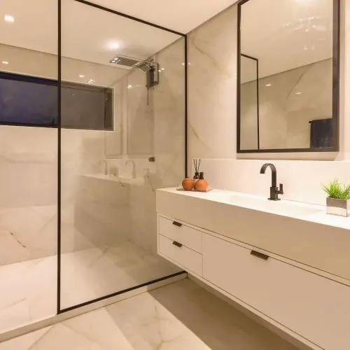 Bagno moderno rifinito con doccia in vetro e rivestimento in marmo